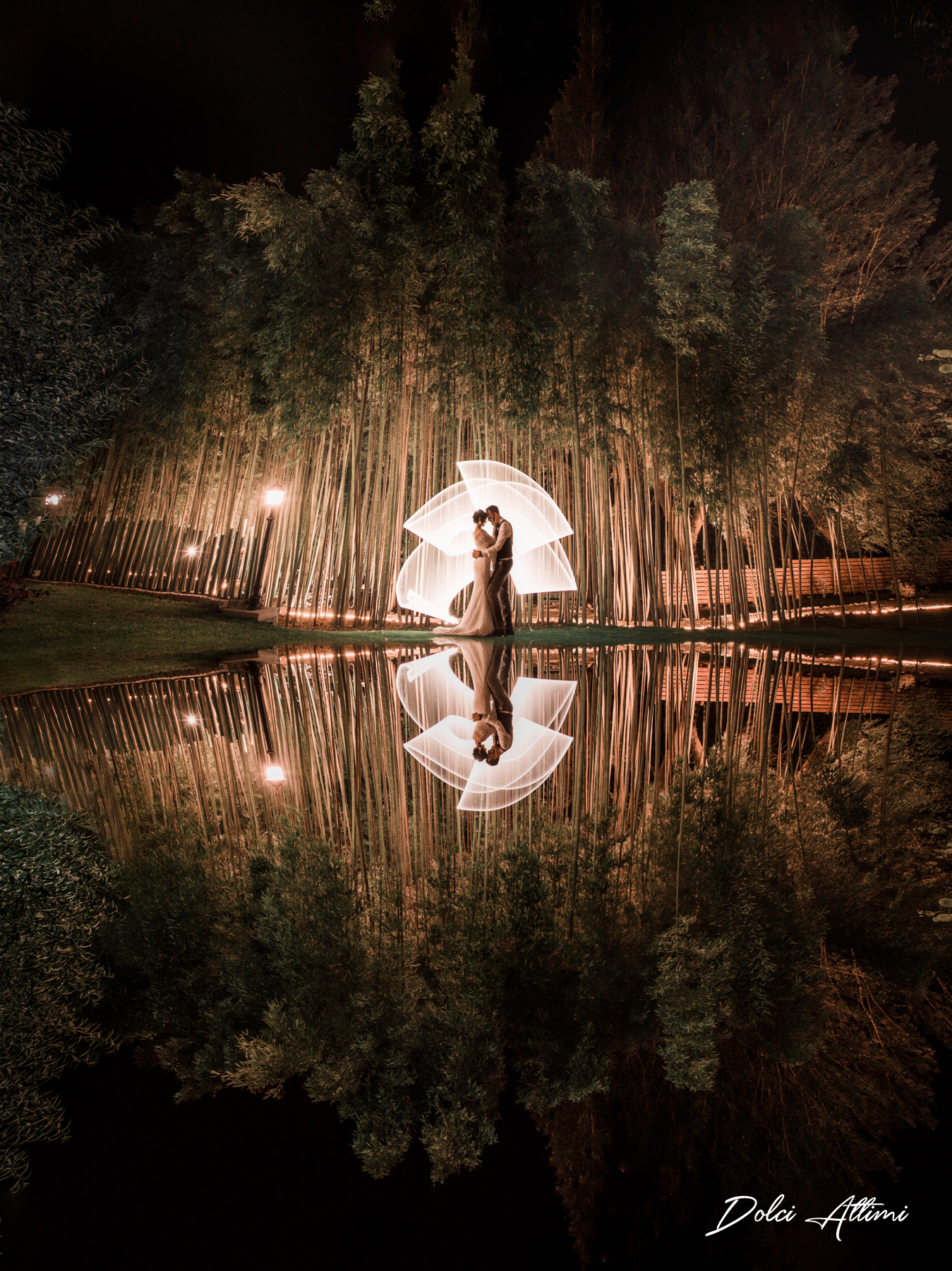 coppia di sposi abbracciati davanti ad un bambuseto di notte e dietro scie luminose create con il lightpainting
