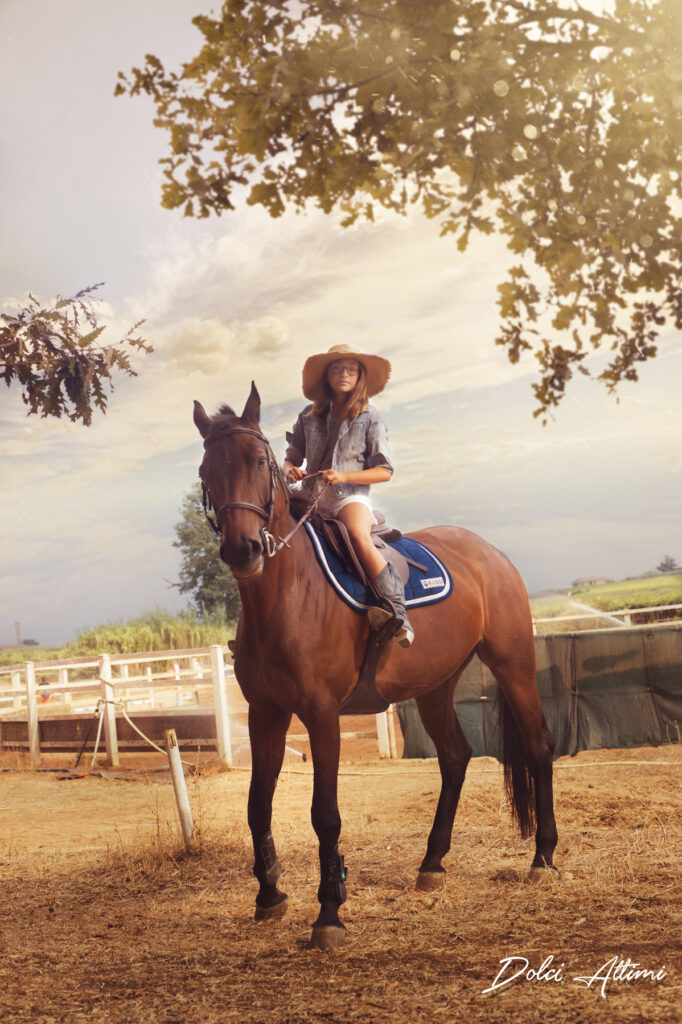servizio fotografico cavallo. Giovane bambina in sella a un cavallo vestita da cowboy